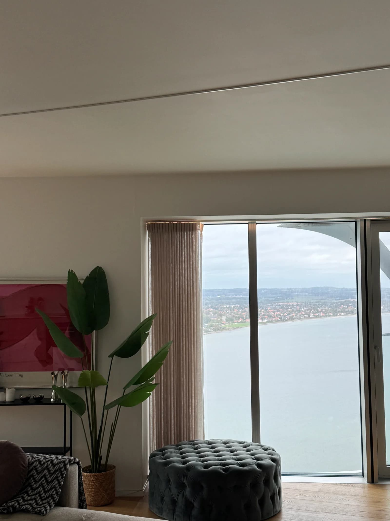 The living room’s curtains and ceiling lighting beside the panoramic windows